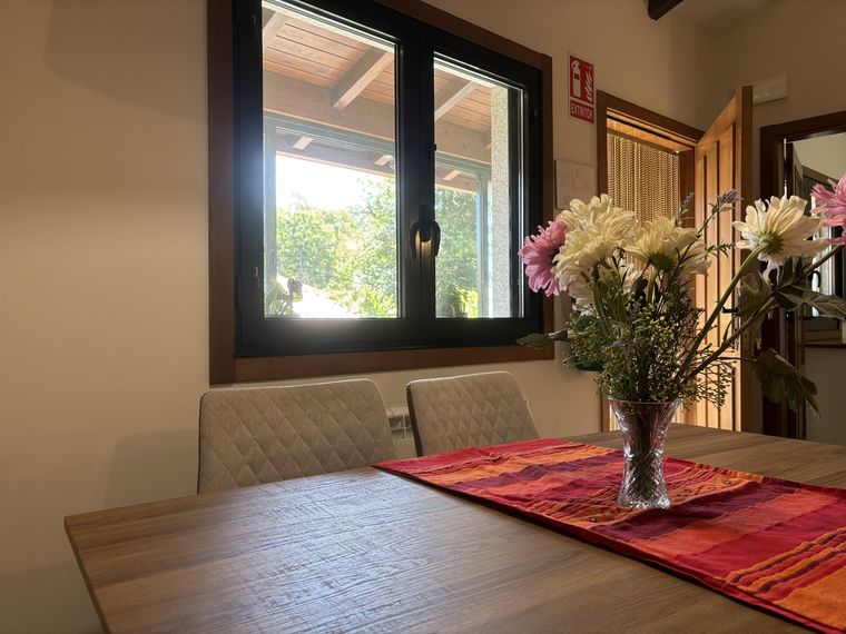 Menjador amb flors vora la finestra · A Casita do Ferreiro